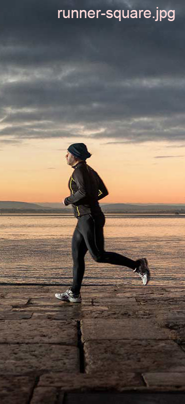 Photograph of a man running along a pier at sunset, with a harbour in the background